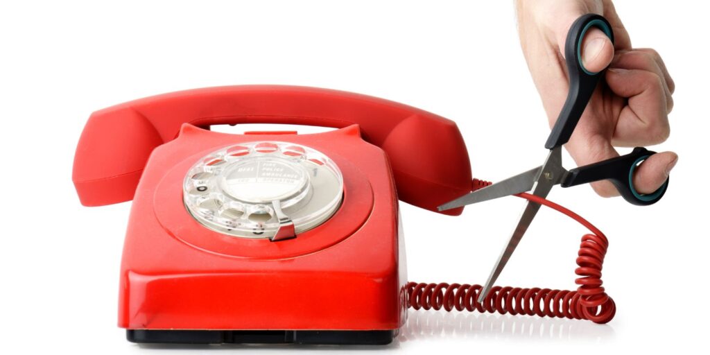 A pair of scissors snipping a phone cord